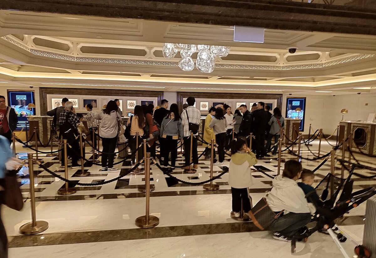 Guests queueing at a large hotel check-in counter with their booking vouchers